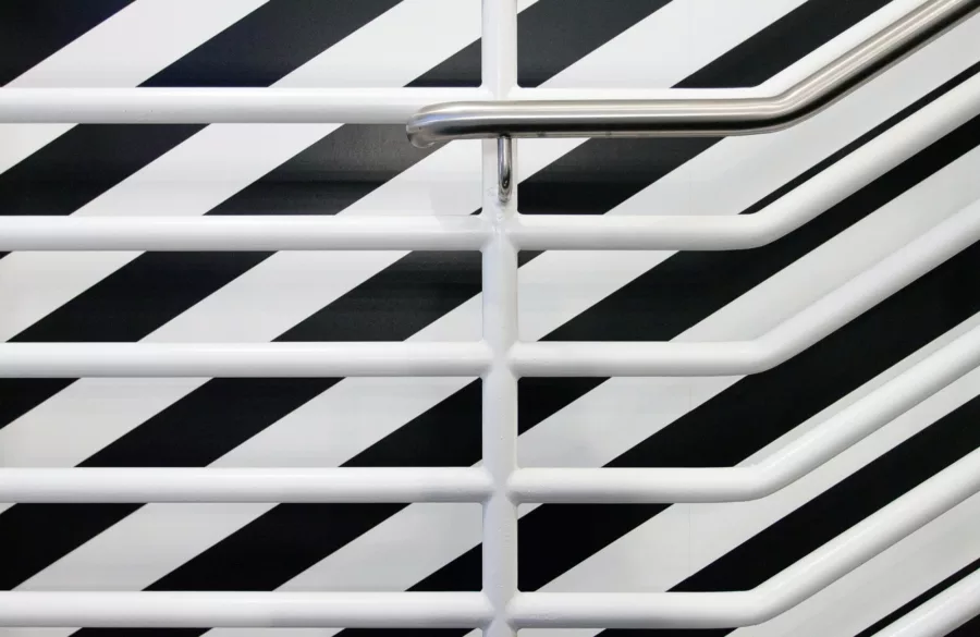 White staircase railing against a black and white striped vinyl graphic on wall.