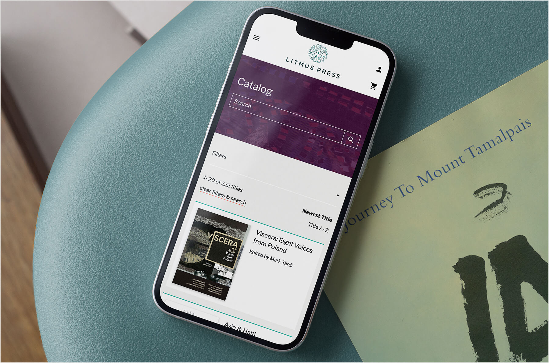 An iPhone rests on a chair with the Litmus Press website open to the Catalog page.