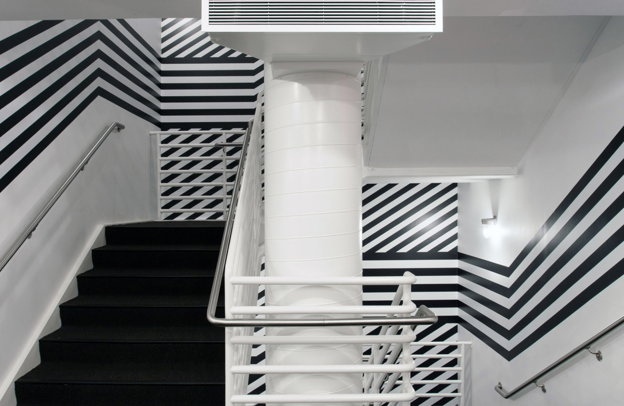 A staircase with walls wrapped in a bold, black and white striped design.