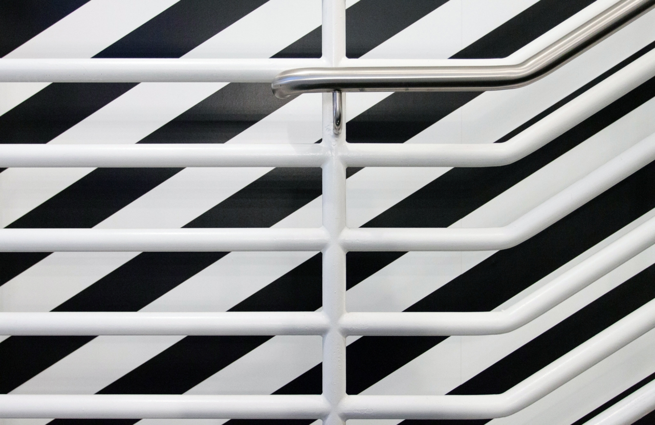 A white staircase railing against a bold black striped design.