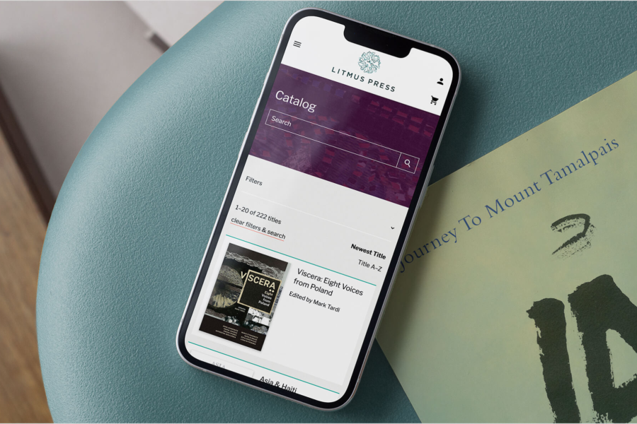 An iPhone rests on a chair with the Litmus Press website open to the Catalog page.