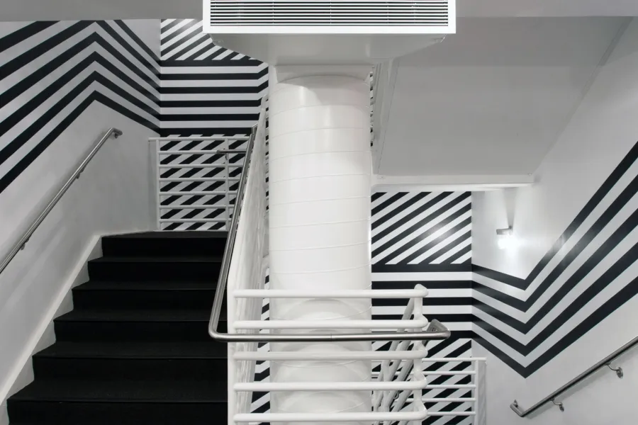 A staircase with walls wrapped in a bold, black and white striped design.